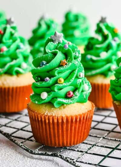 Rows of Christmas tree cupcakes on a wire baking rack.