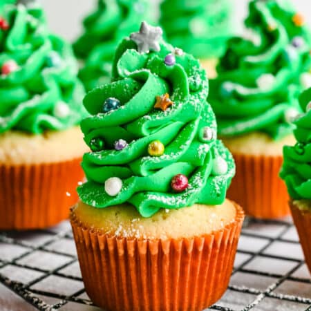 Rows of Christmas tree cupcakes on a wire baking rack.