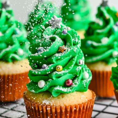 Powdered sugar drizzling onto Christmas tree cupcakes.
