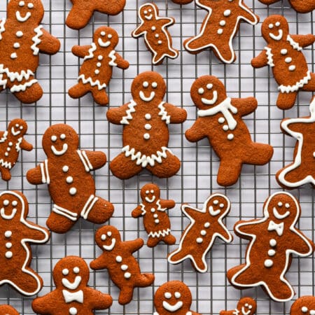 Large and small decorated gingerbread men on a wire rack.