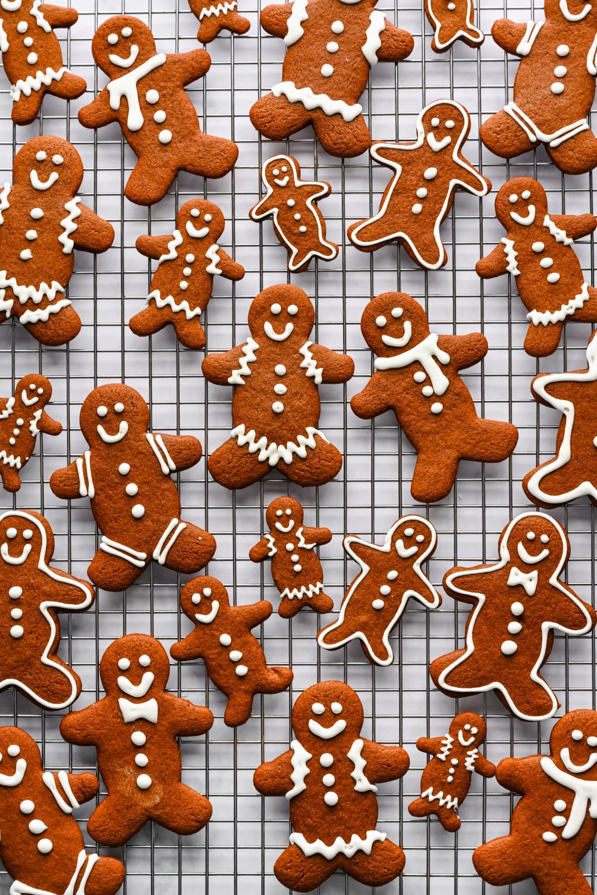 Large and small decorated gingerbread men on a wire rack.