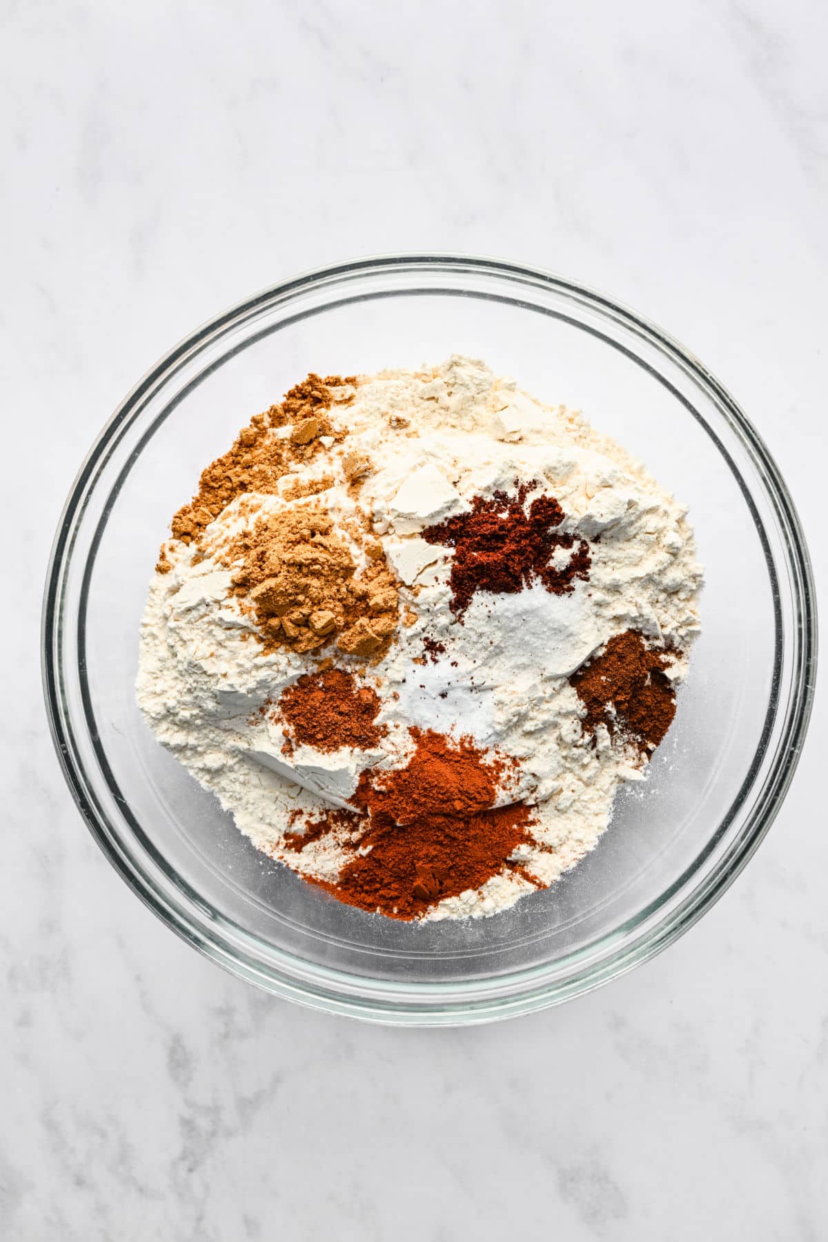 Dry ingredients for gingerbread men in a glass mixing bowl. 