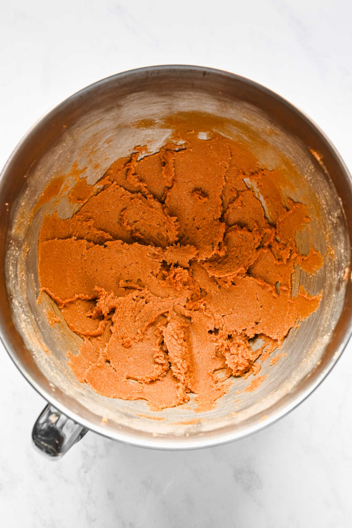 Butter and brown sugar creamed in a silver mixing bowl. 