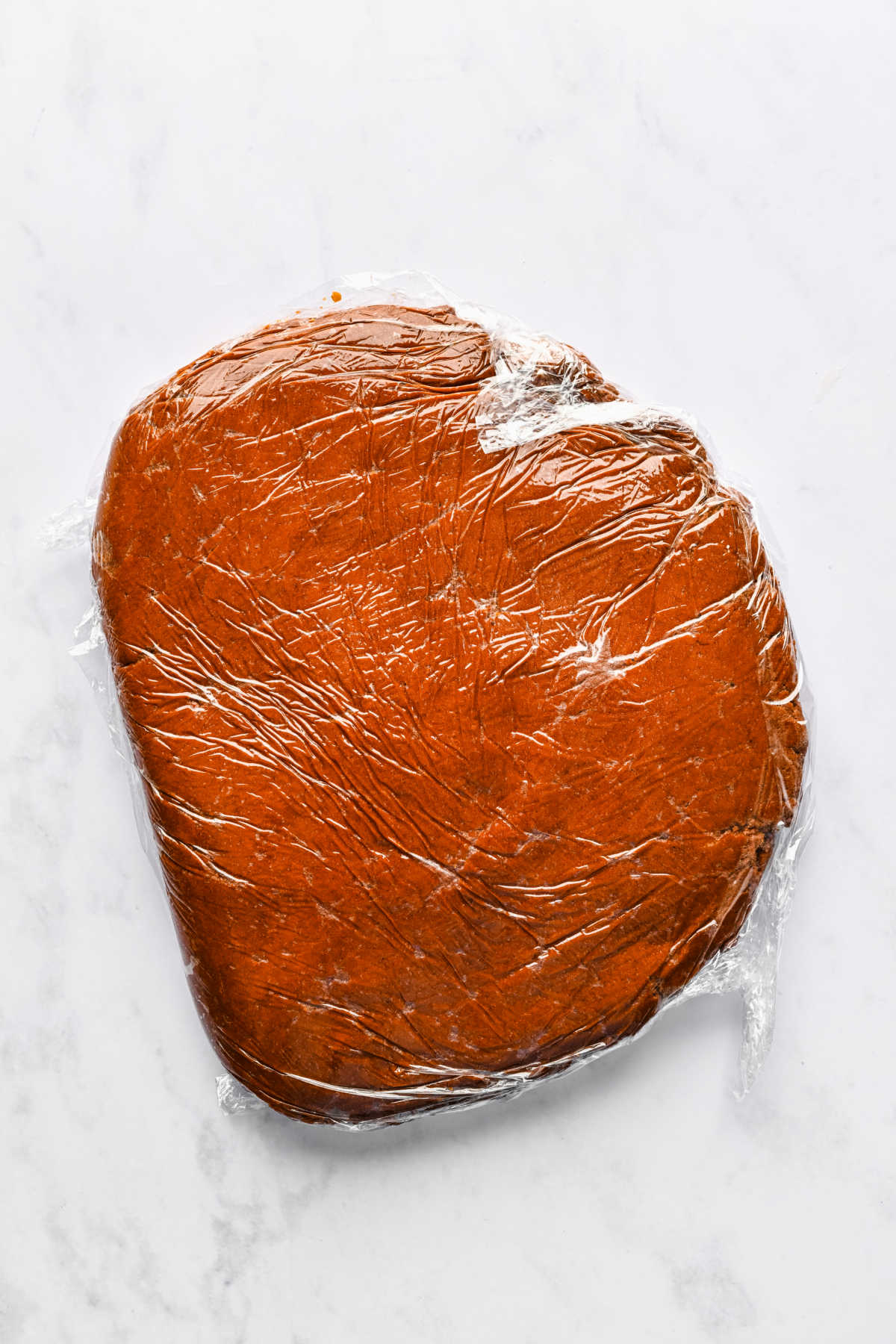 A portion of gingerbread men cookie dough wrapped in plastic wrap.