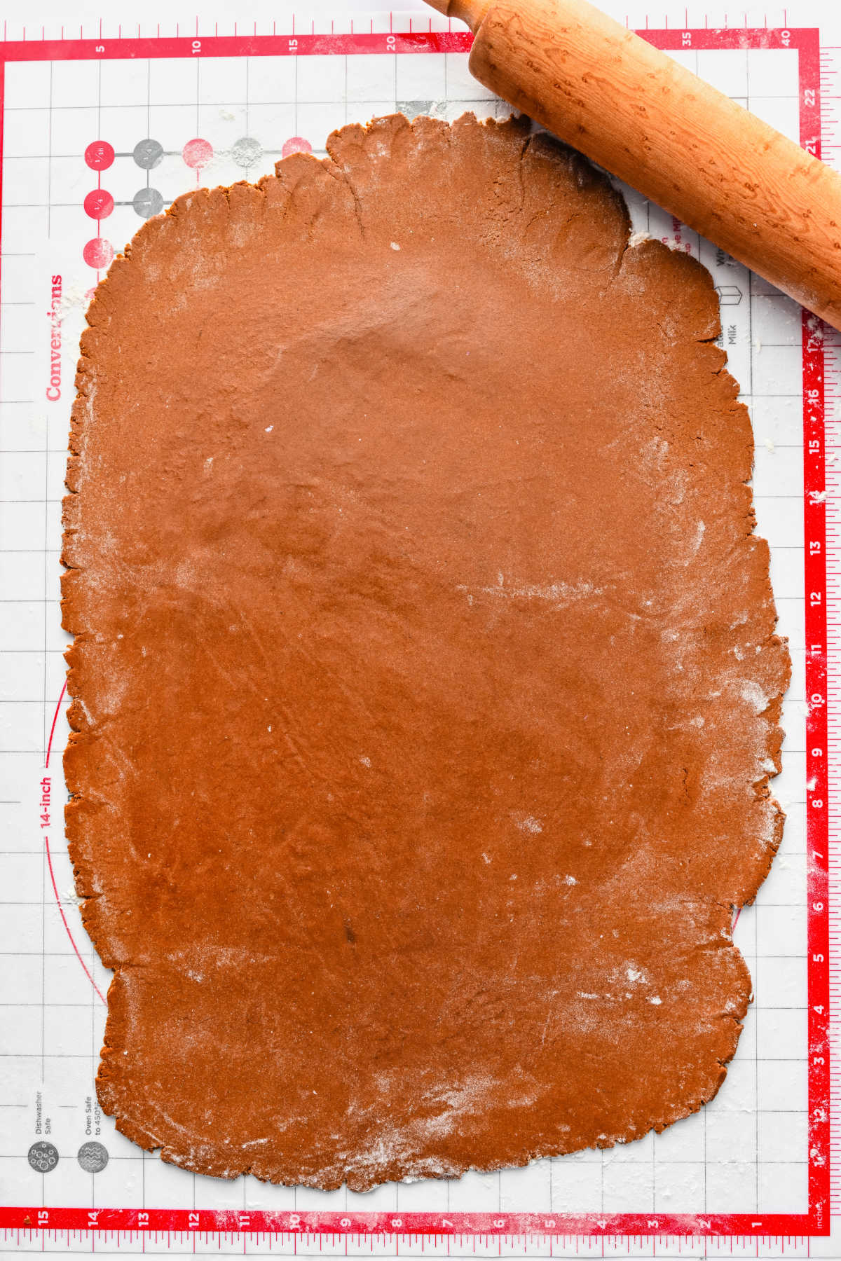 Rolled out gingerbread men cookie dough on a silicone baking mat. 