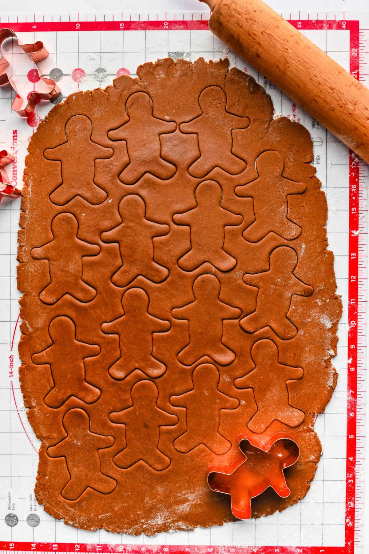 Cookie cutter cutting out gingerbread men from rolled out cookie dough.