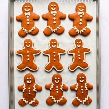 Gingerbread men decorated with royal icing on a baking sheet.