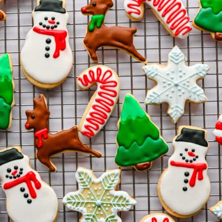 Cut out sugar cookies decorated with royal icing on a wire cooling rack.