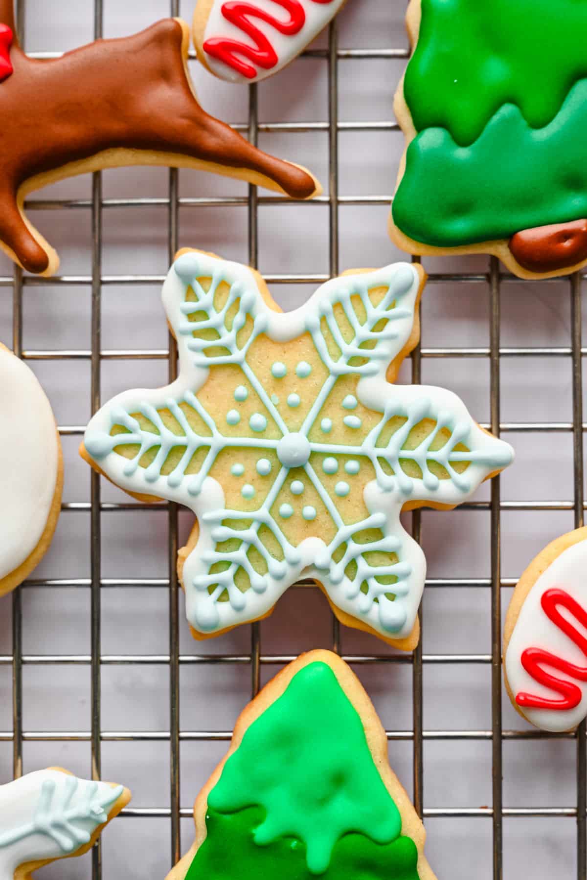 A cut out sugar cookie decorated like a snowflake with blue royal icing.