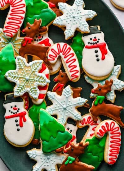 Decorated Christmas cut out sugar cookies in a pile on a platter.