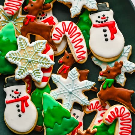 Decorated Christmas cut out sugar cookies in a pile on a platter.