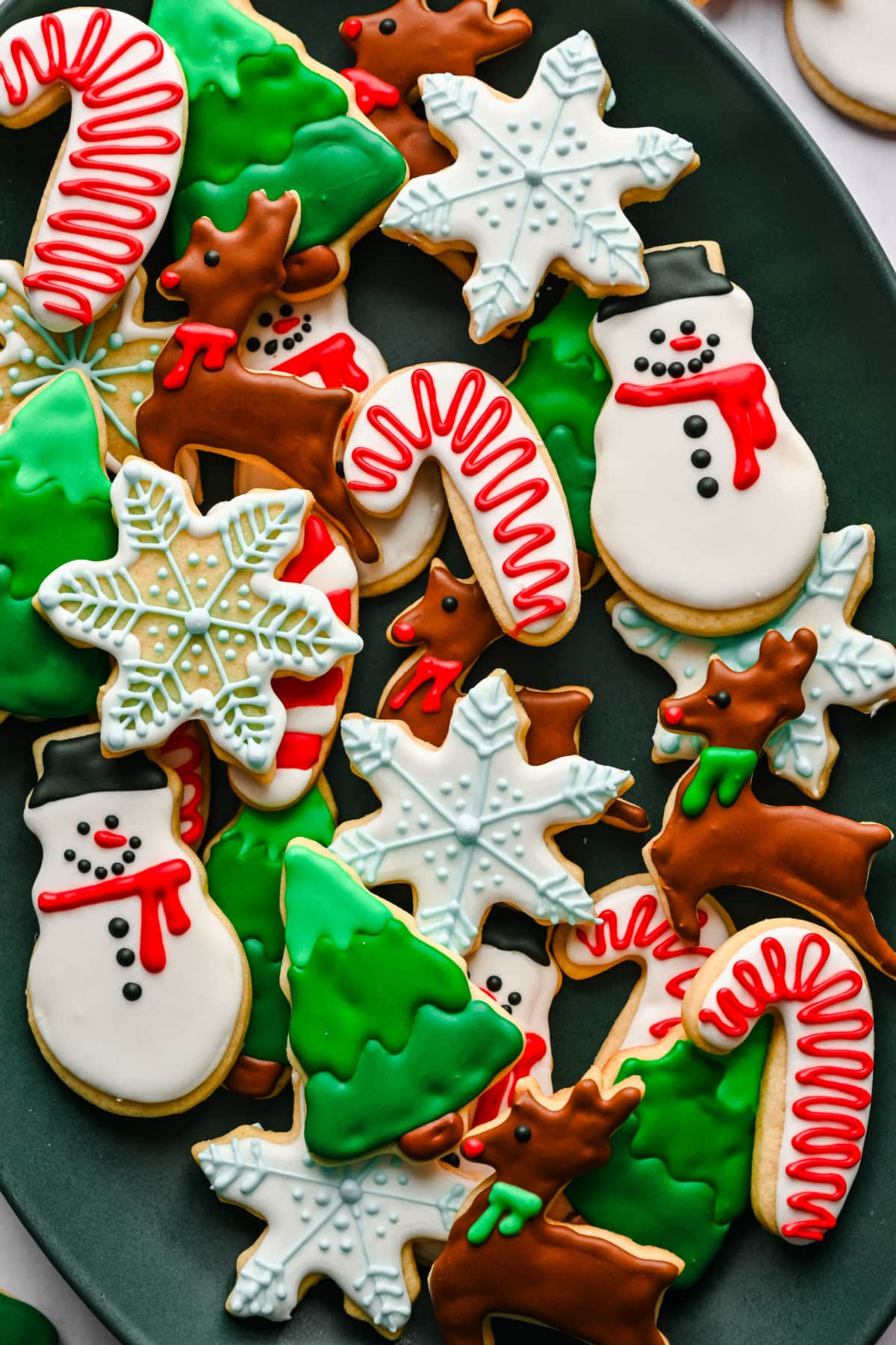Decorated Christmas cut out sugar cookies in a pile on a platter.