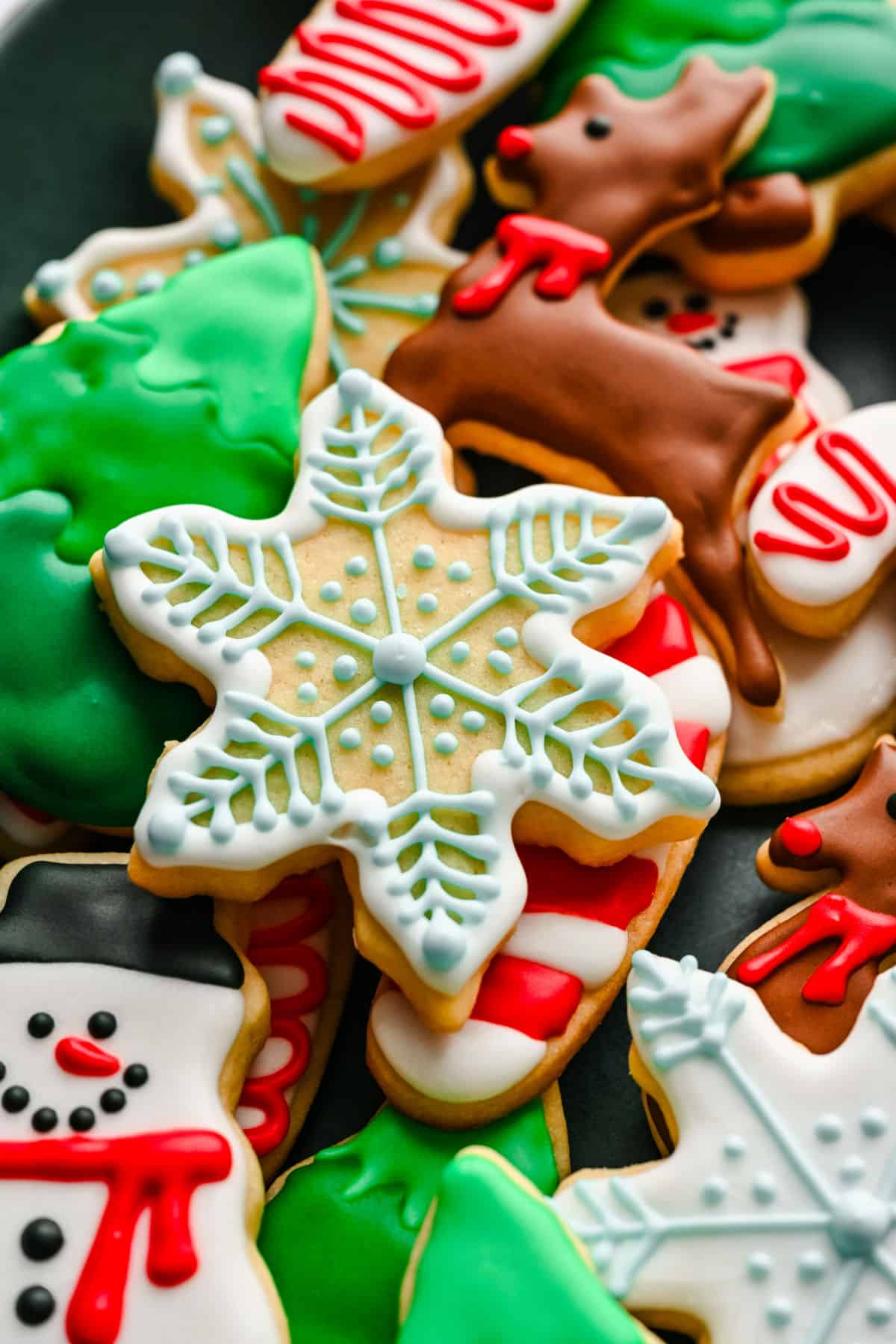 A snowflake cut out sugar cookie on top of other decorated sugar cookies.
