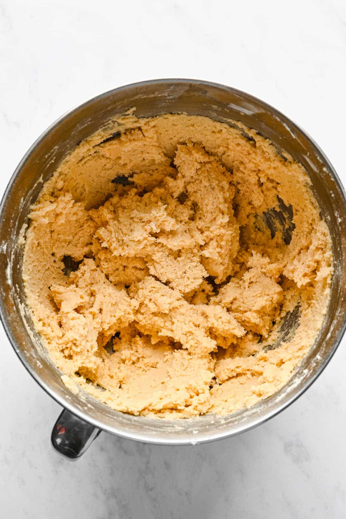 Sugar cookie dough in a silver mixing bowl.