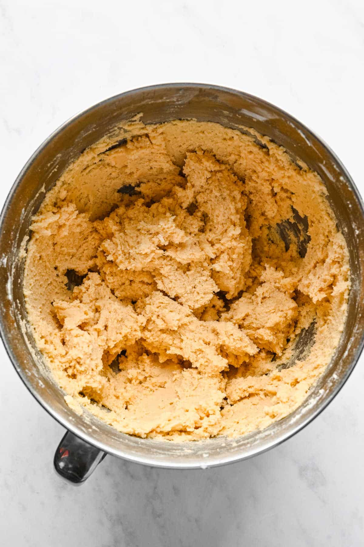 Sugar cookie dough in a silver mixing bowl. 