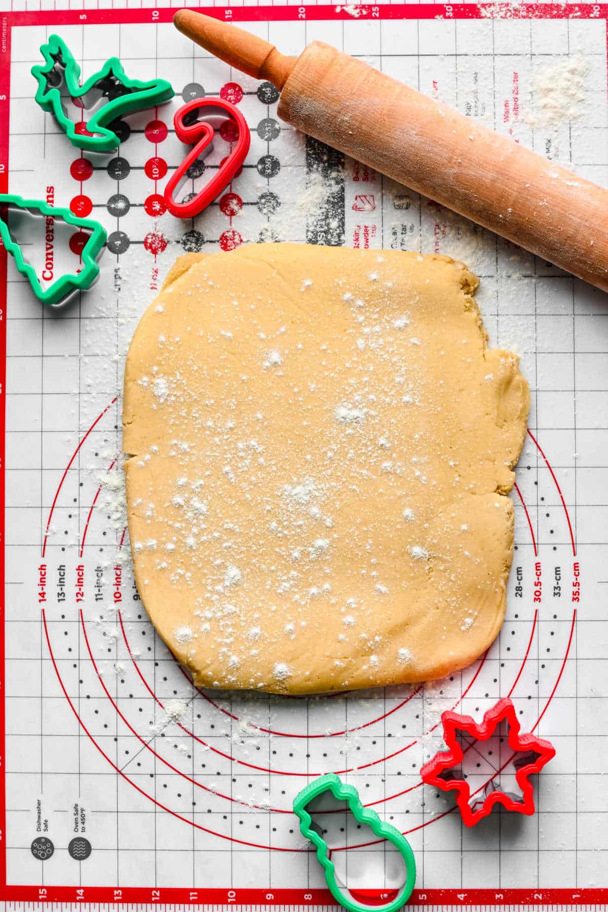 Cut out sugar cookie dough on a rolling mat.