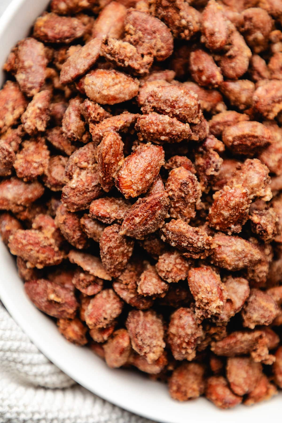 Close up photo of candied cinnamon almonds in a white dish.
