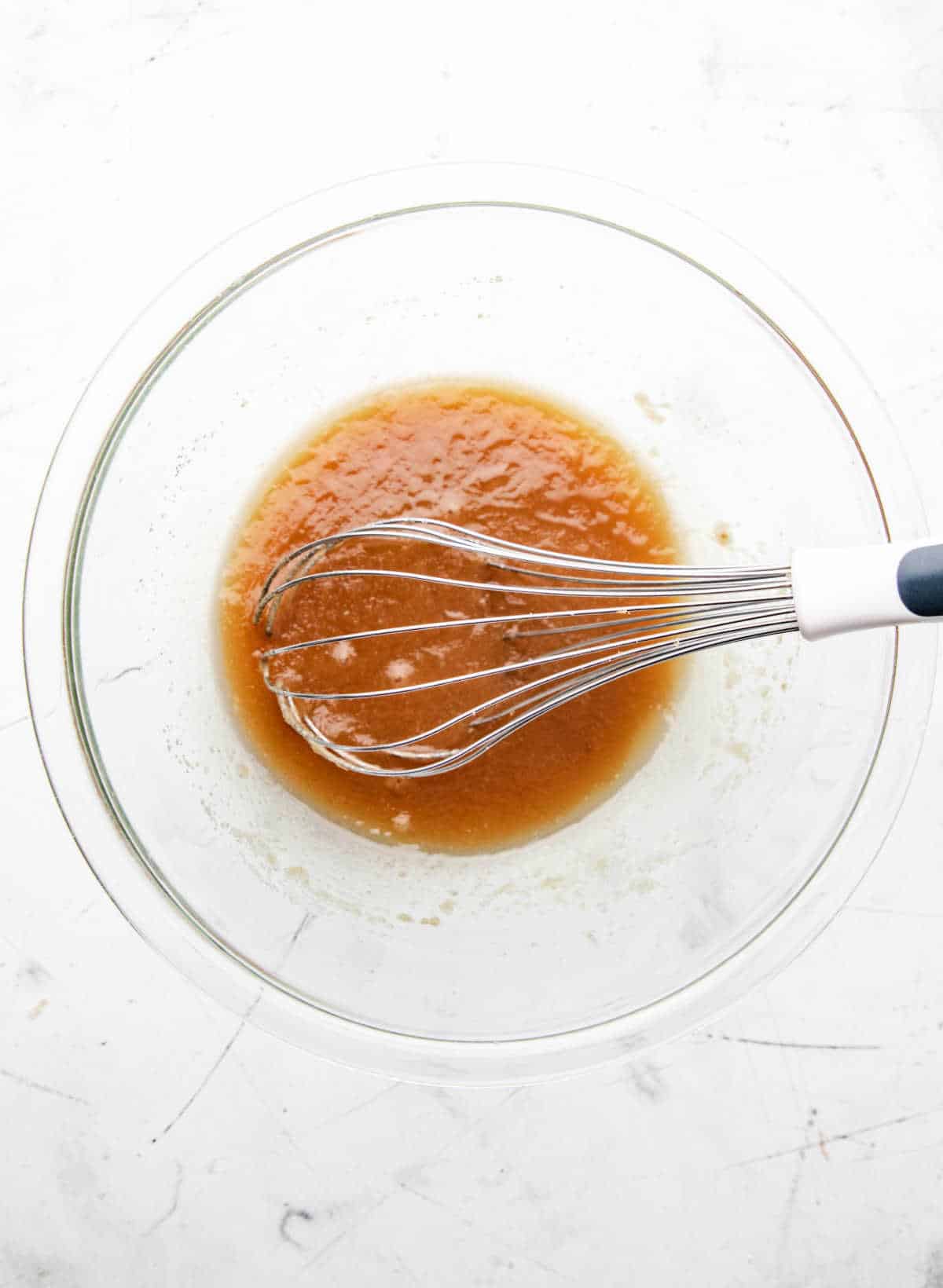 Melted butter and sugars mixed in a glass mixing bowl. 