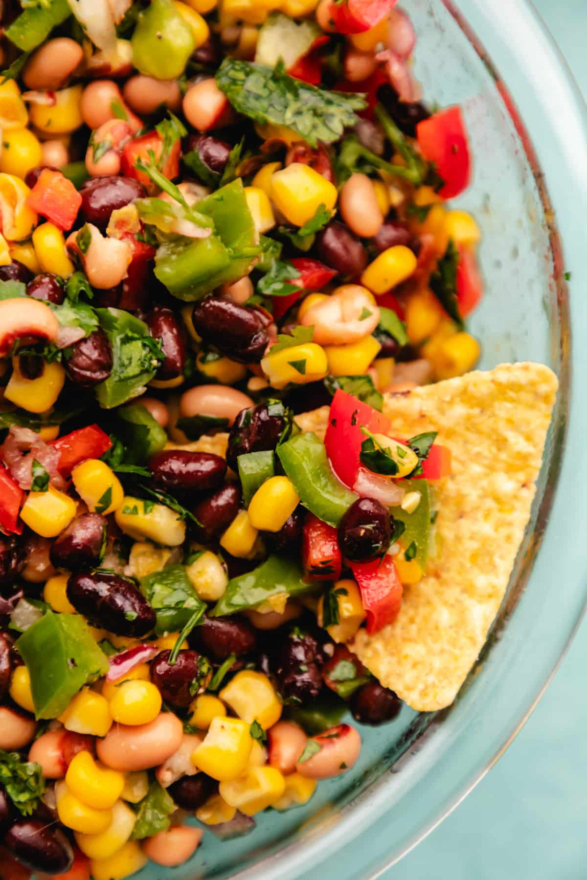 A tortilla chip holding a scoop of cowboy caviar. 