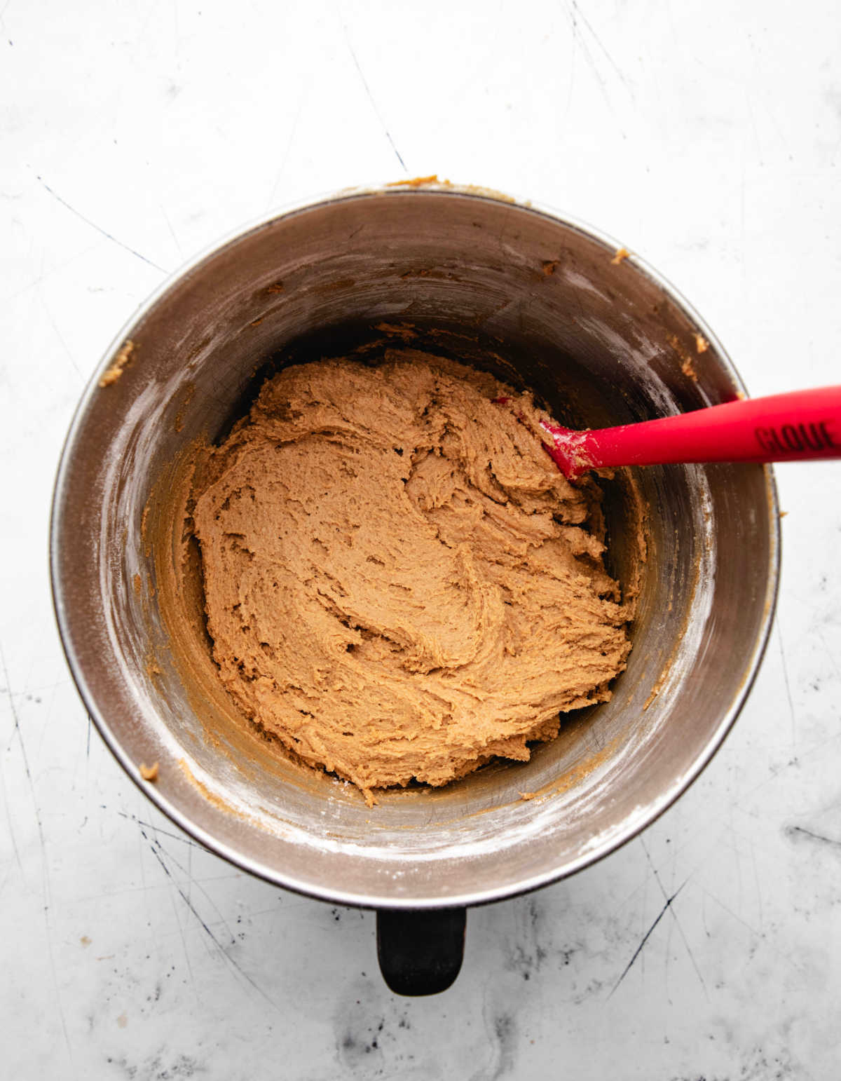 Chewy ginger molasses cookie dough in a silver mixing bowl. 