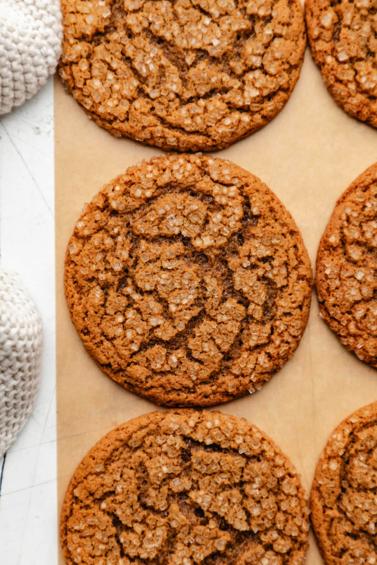 Rows of ginger molasses cookies on a sheet of brown parchment paper. 