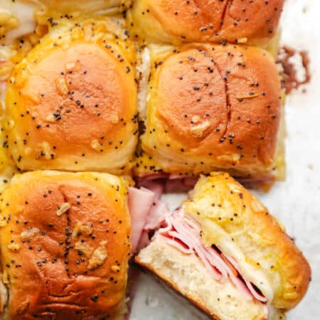 A baked ham and cheese slider turned on its side next to the other sandwiches.
