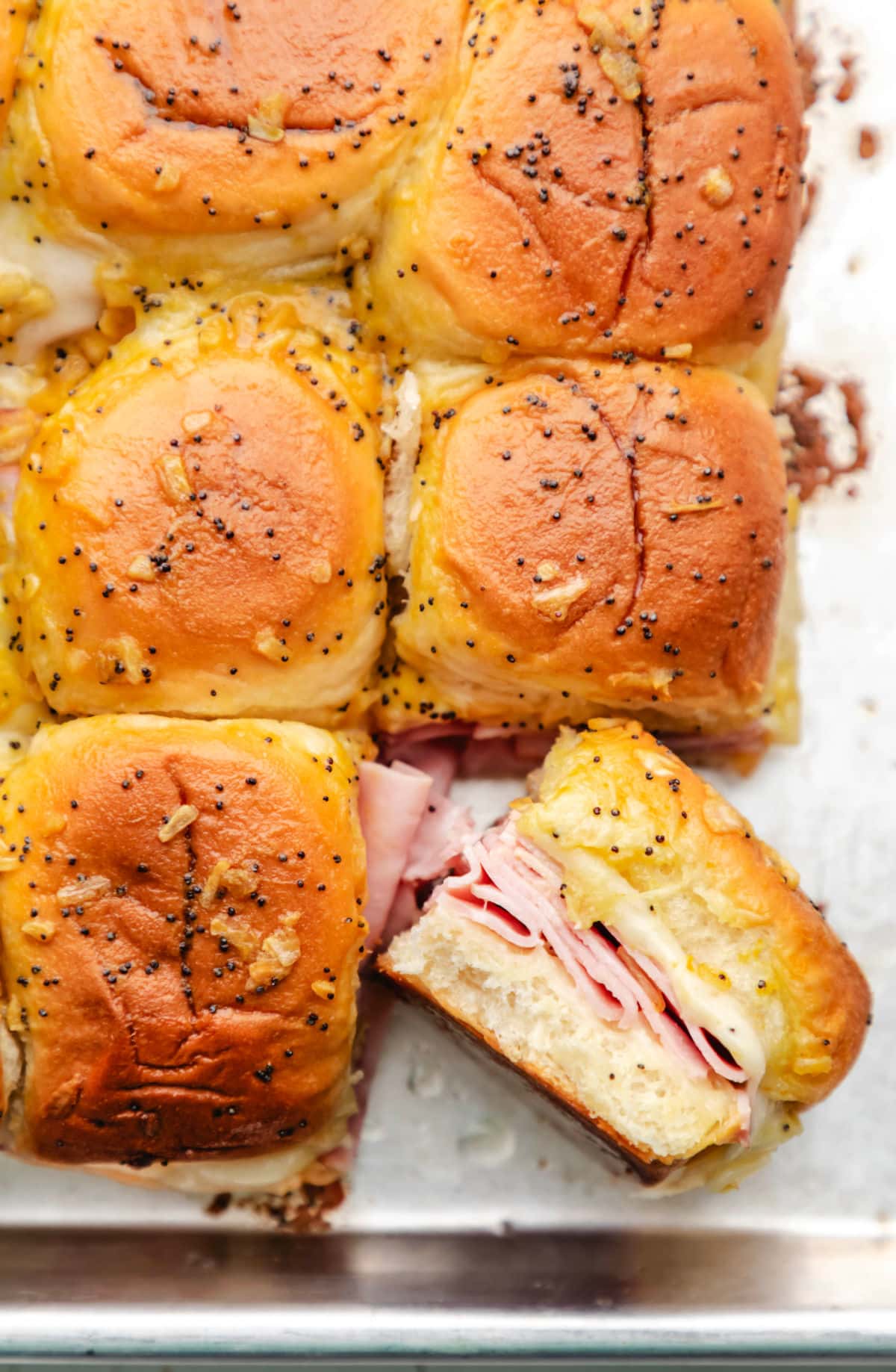 A baked ham and cheese slider turned on its side next to the other sandwiches. 