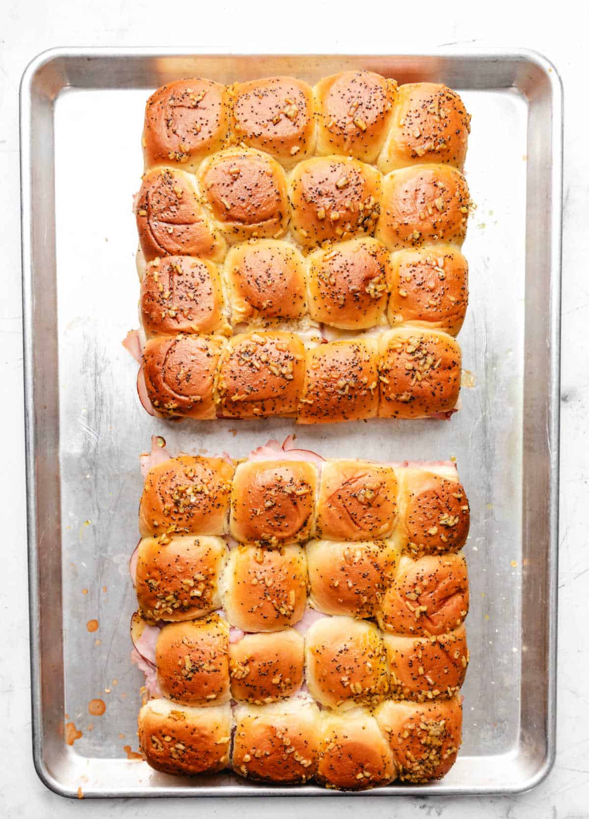 Unbaked ham and cheese sandwiches on a baking sheet. 