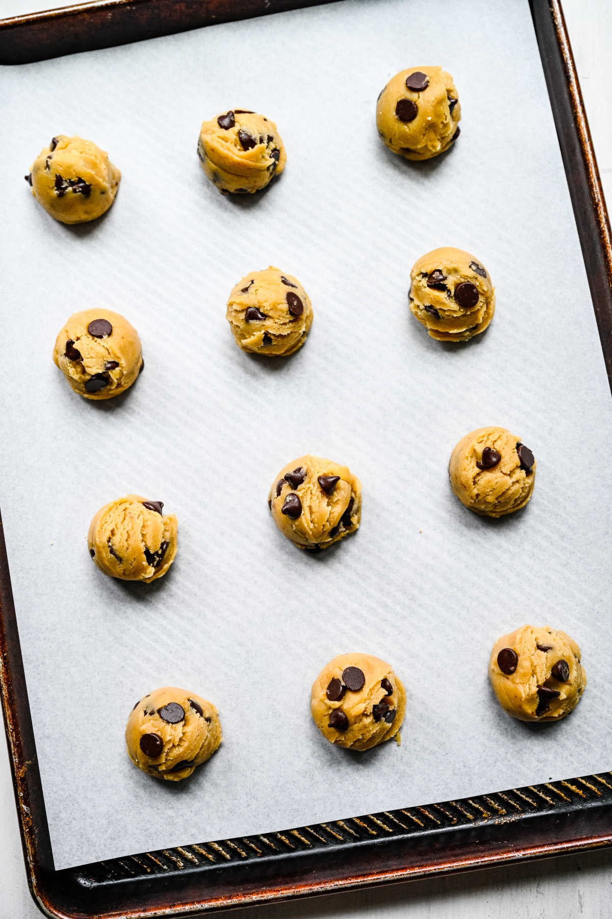 Scoops of chewy chocolate chip cookie dough on a baking sheet.