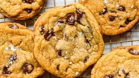 Chewy chocolate chip cookies overlapping on a wire cooling rack.