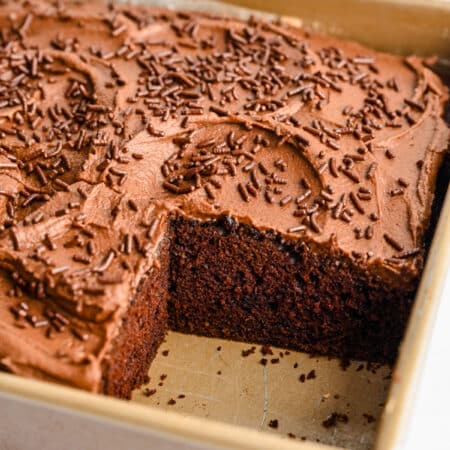 Chocolate mayonnaise cake in a pan with a big piece cut out.