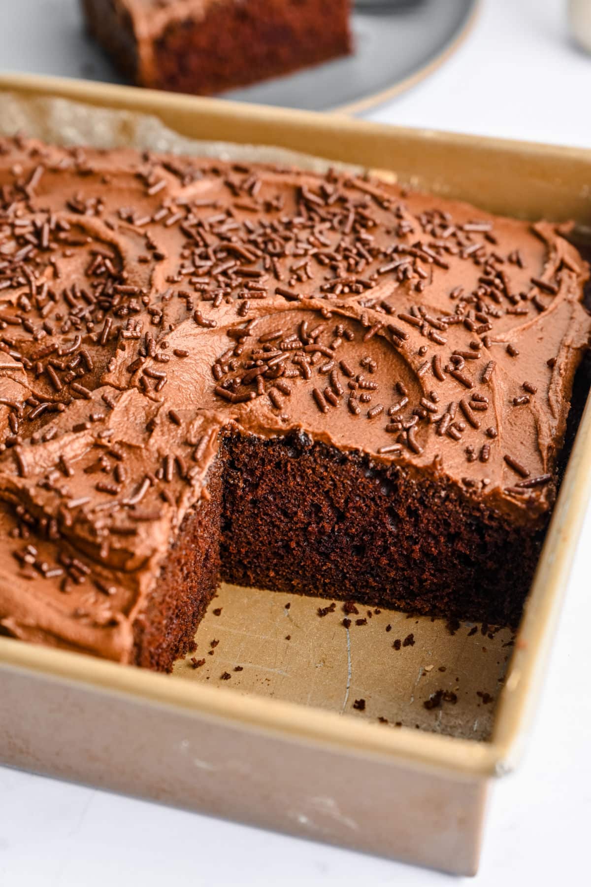 Chocolate mayonnaise cake in a pan with a big piece cut out.