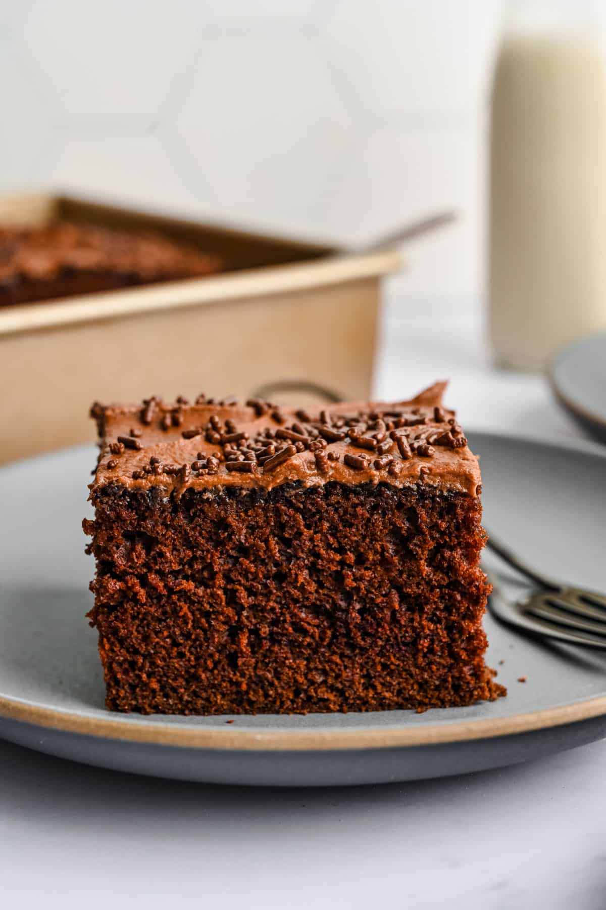 A piece of chocolate mayonnaise cake on a plate with a fork next to it.