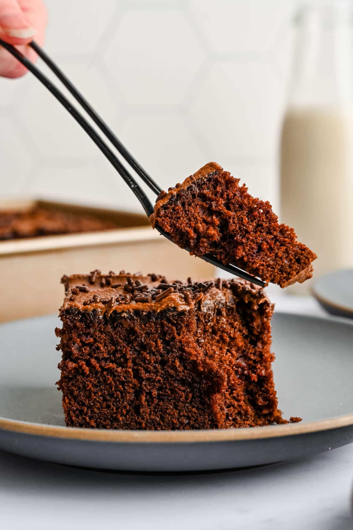 A fork taking a bite of a slice of chocolate mayonnaise cake.