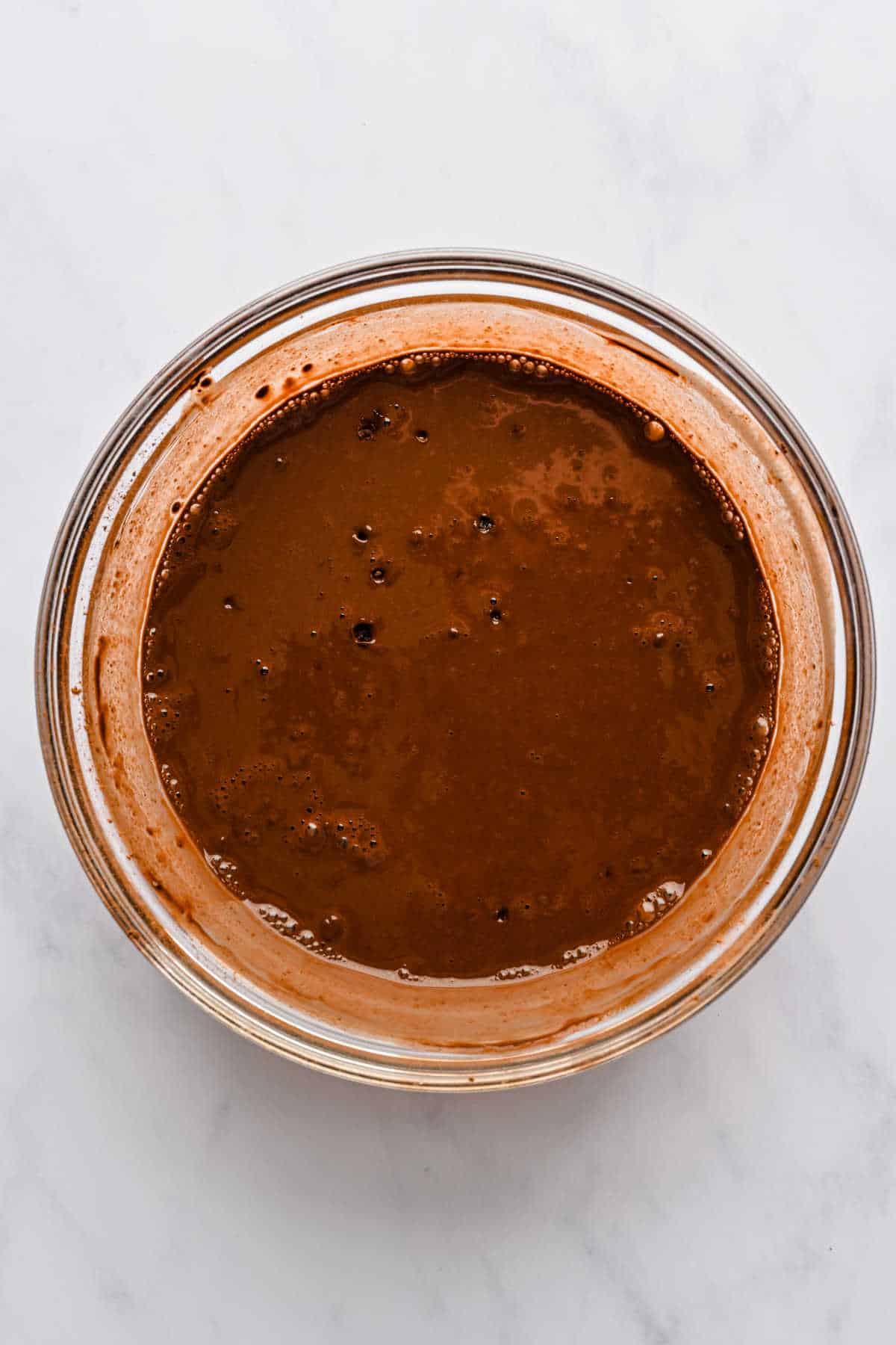 Hot water and cocoa powder stirred together in a small mixing bowl.