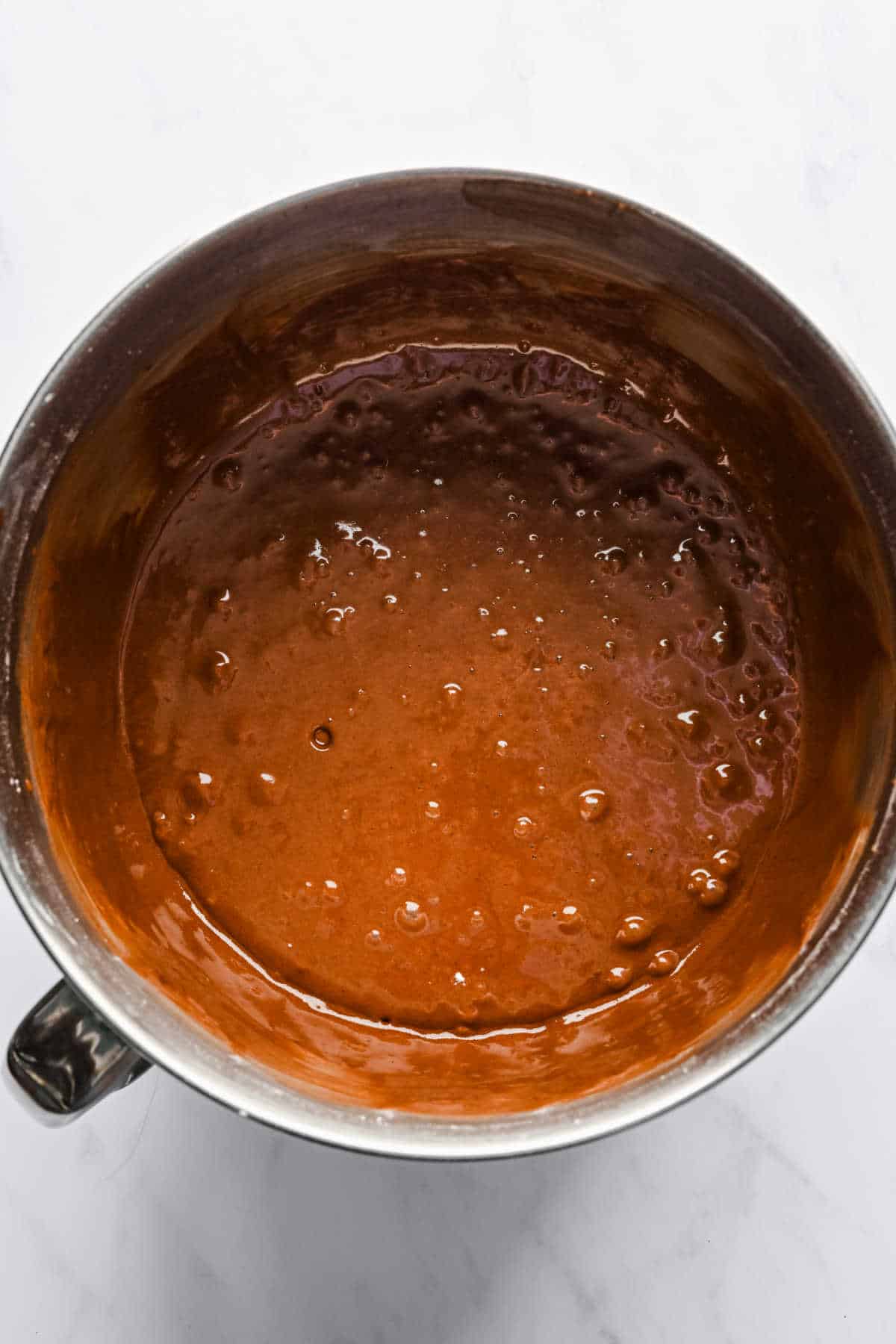 Chocolate mayonnaise cake batter in a silver mixing bowl. 
