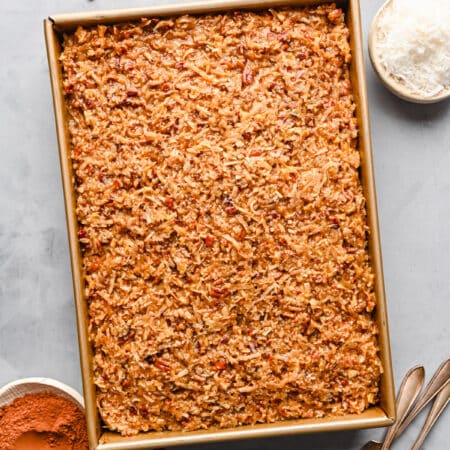 German chocolate sheet cake in the pan surrounded by forks and ingredients in dishes.
