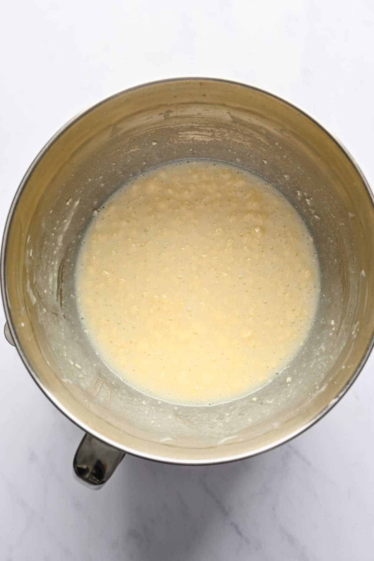Yogurt and butter beaten together in a silver mixing bowl. 