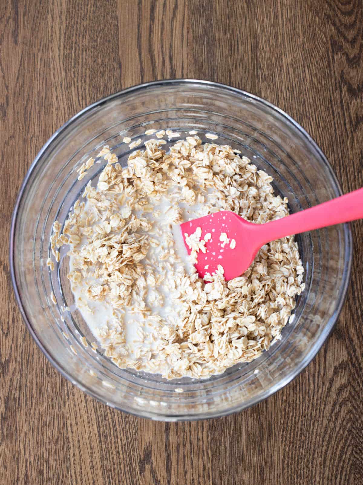 Oats and milk stirred together in a glass mixing bowl. 