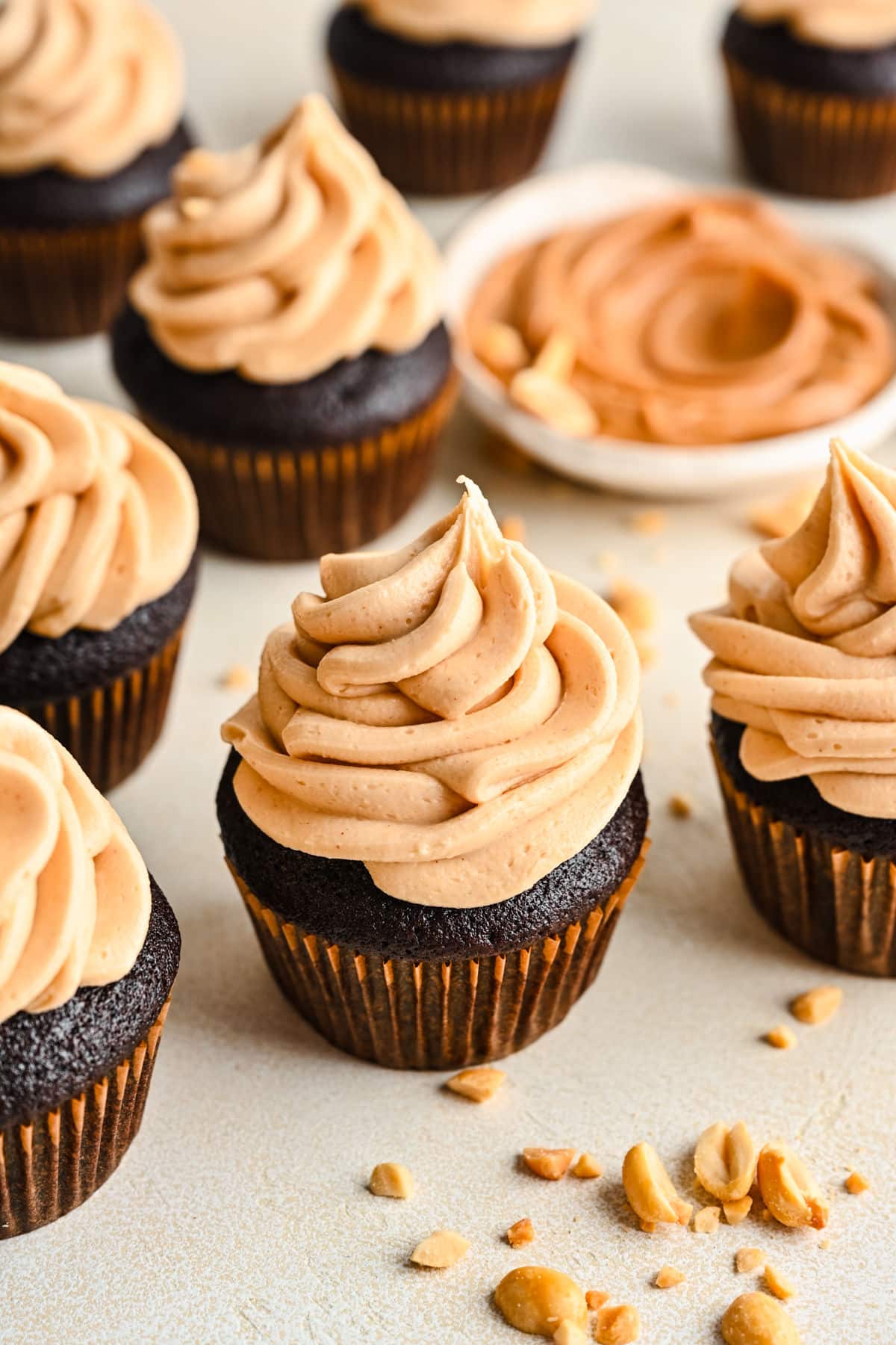 Peanut butter frosted chocolate cupcakes next to a dish of peanut butter.