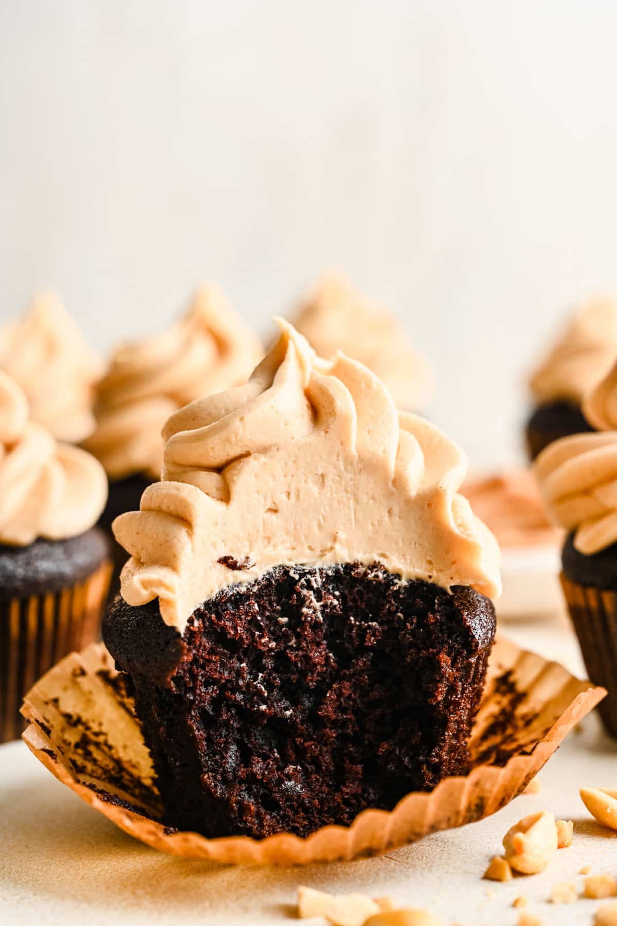 A chocolate cupcake topped with peanut butter frosting with a big bite missing.