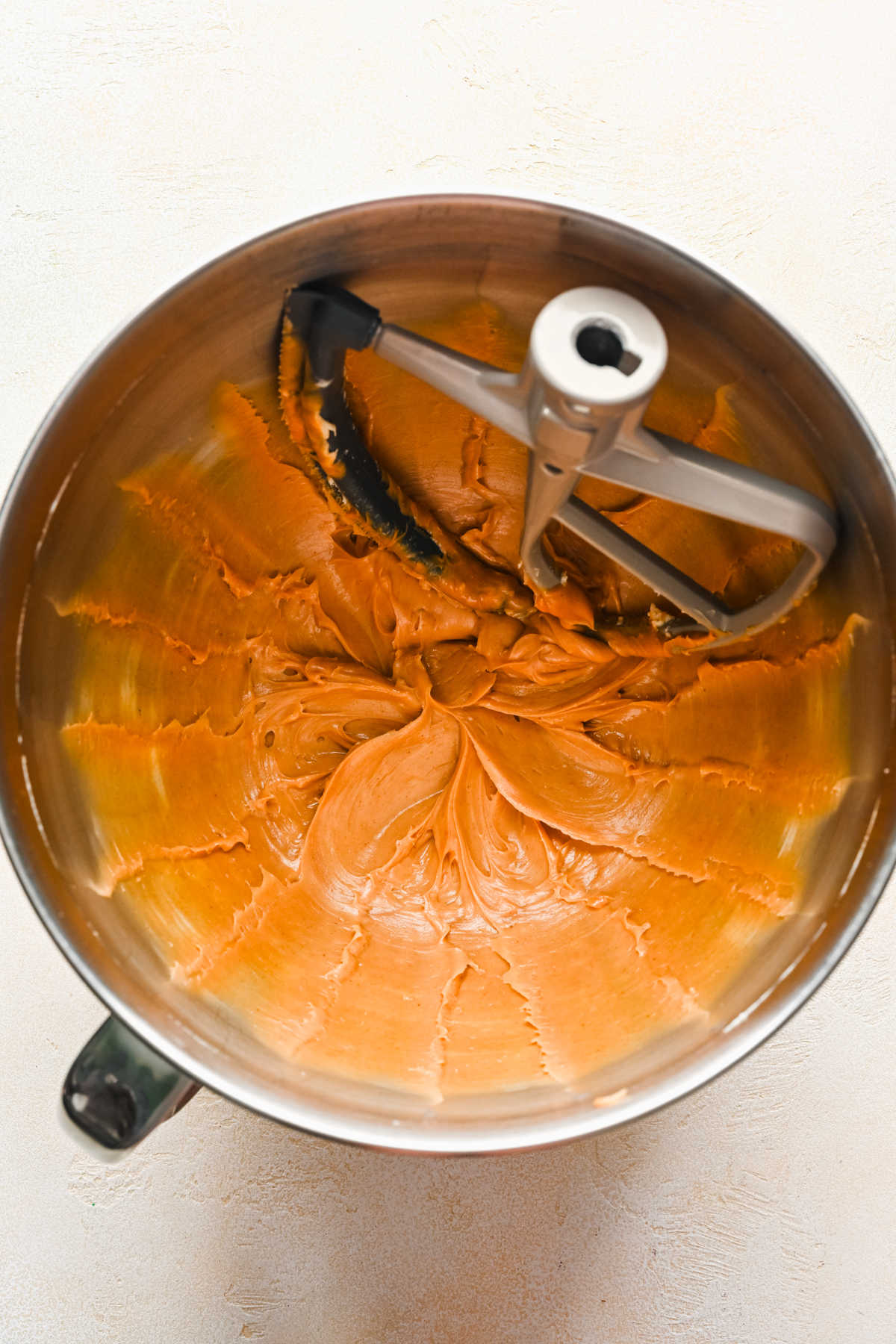 Peanut butter and butter beaten together in a silver mixing bowl. 