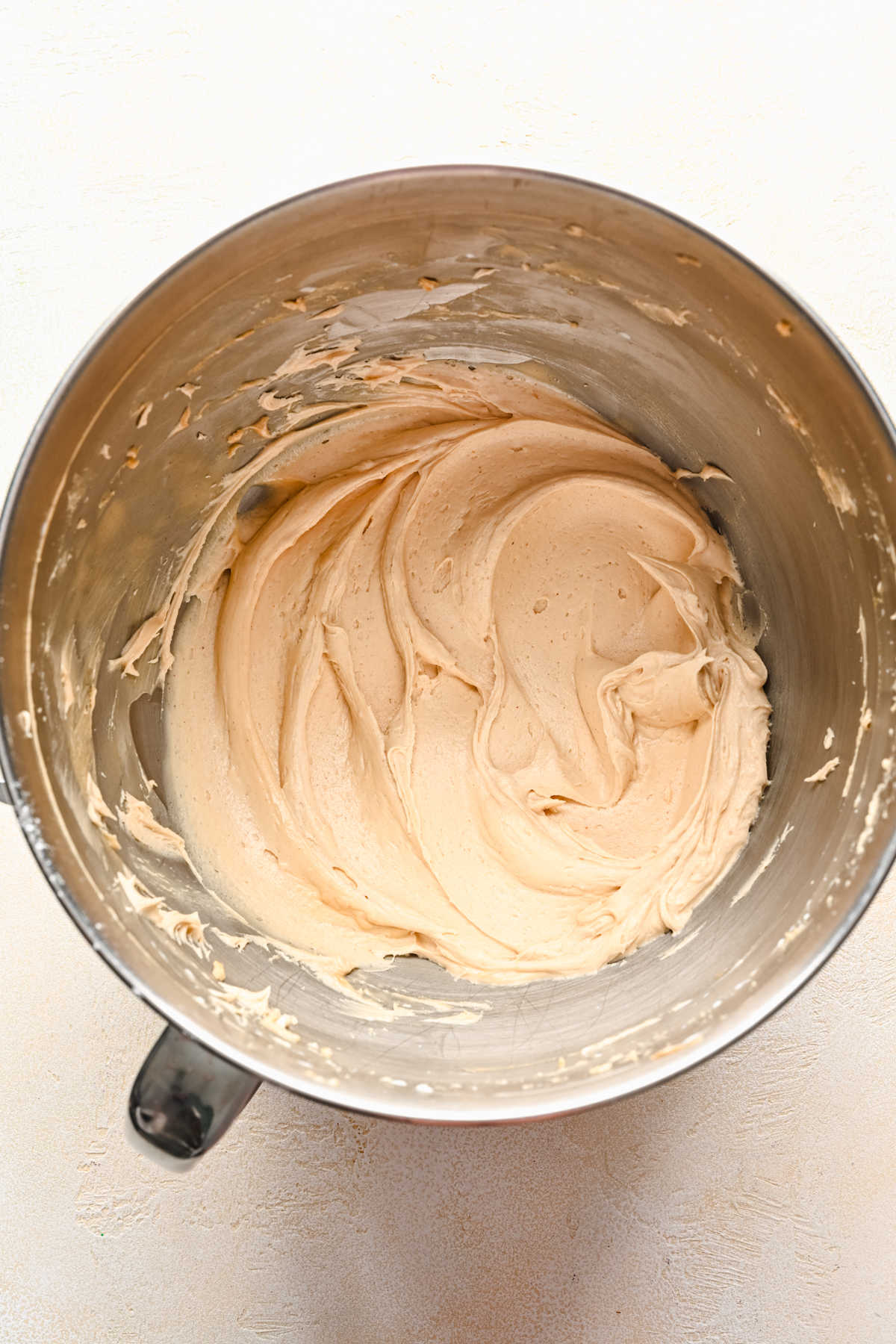 Peanut butter frosting in a silver mixing bowl. 