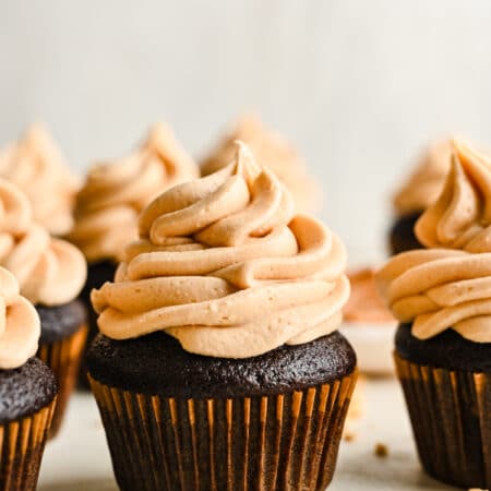 Peanut butter frosting on rows of chocolate cupcakes.