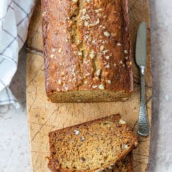 Two slices of banana nut bread next to the loaf of banana bread.