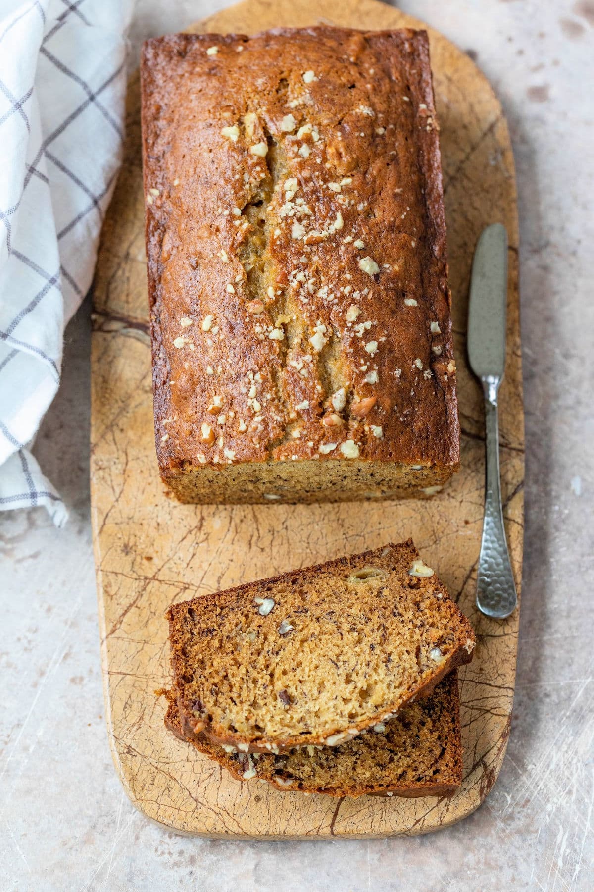 Two slices of banana nut bread next to the loaf of banana bread. 