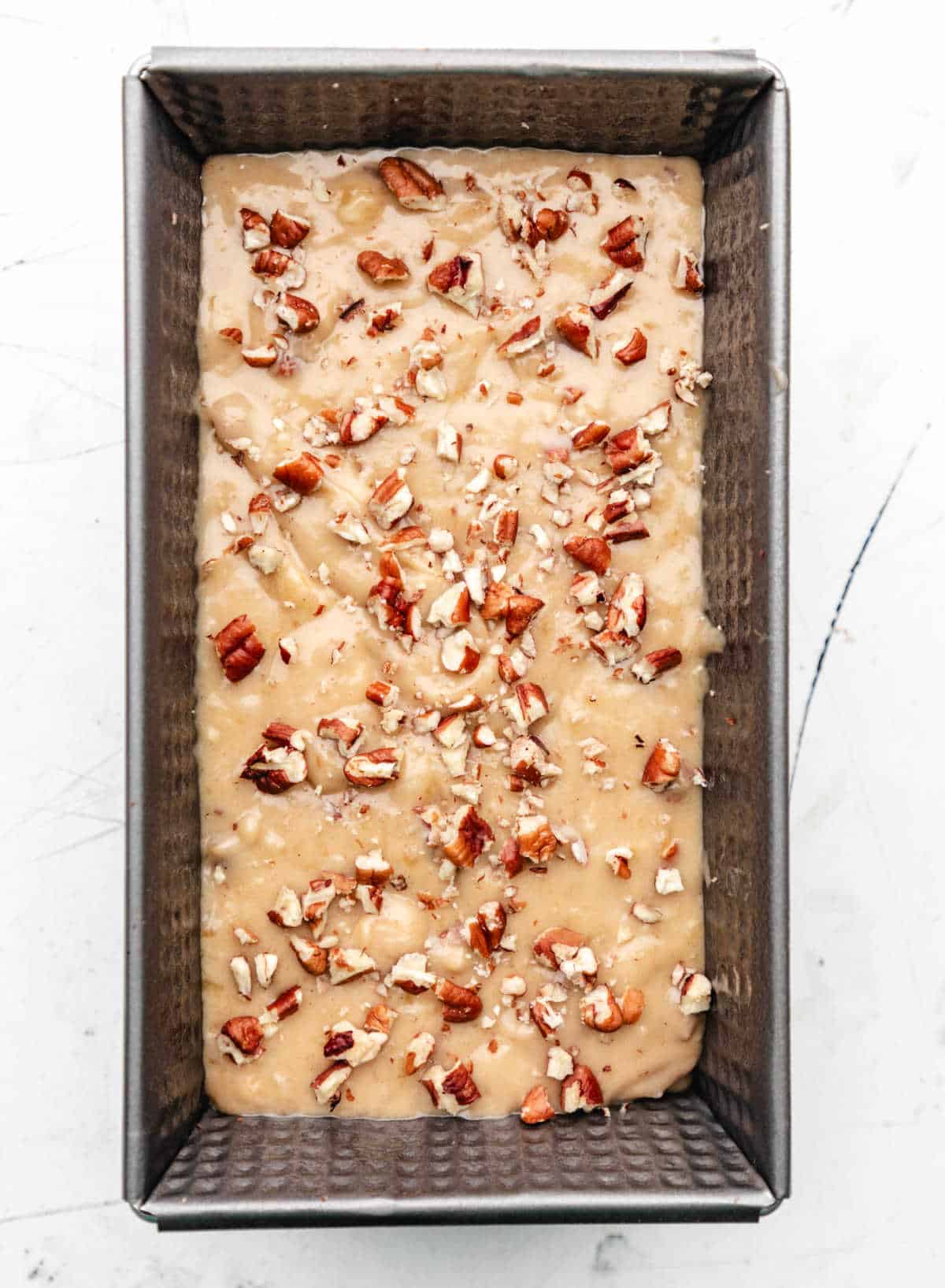 Chopped pecans on top of banana nut bread batter. 