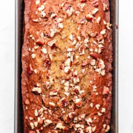 A loaf of banana nut bread in a metal loaf pan.