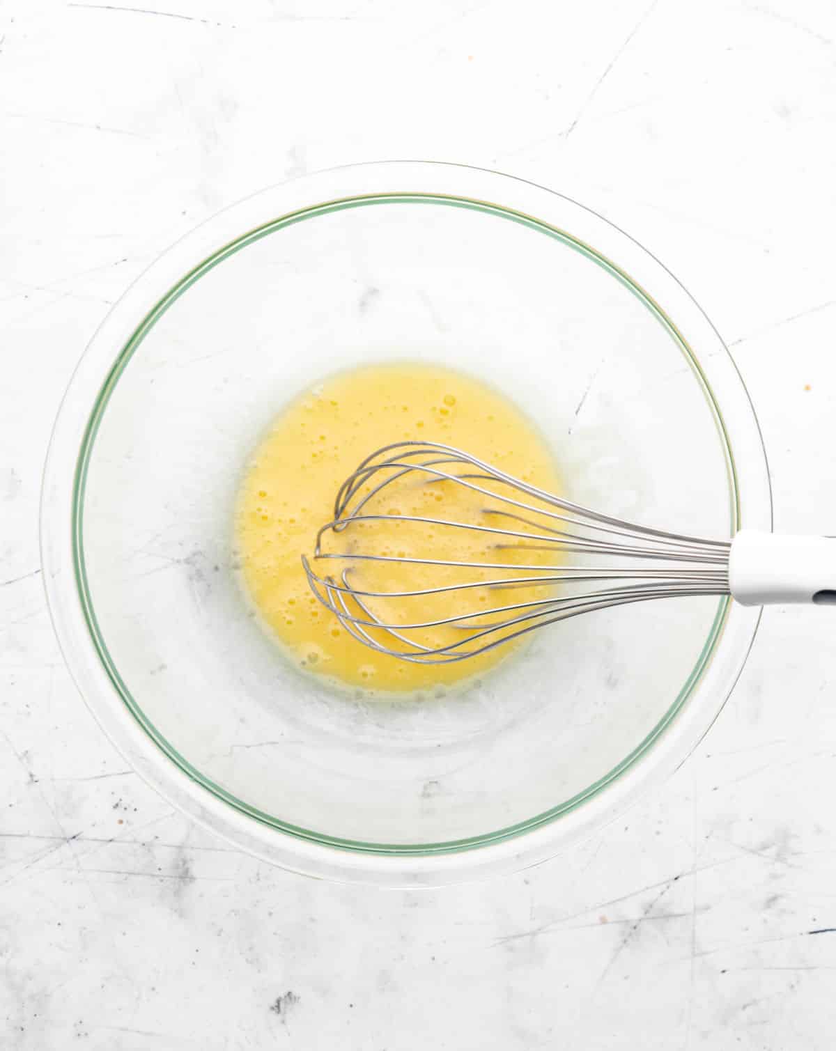 Egg and oil whisked together in a glass mixing bowl. 
