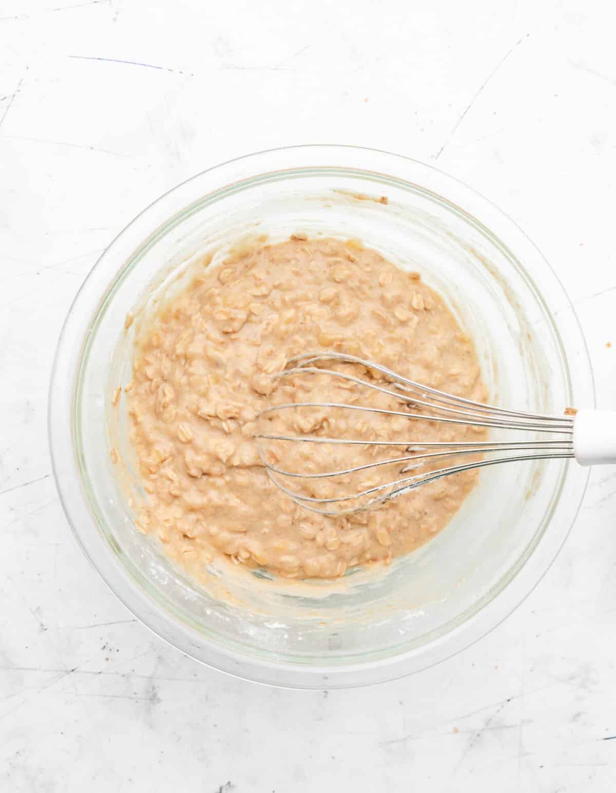 Banana oatmeal muffin batter in a glass mixing bowl. 